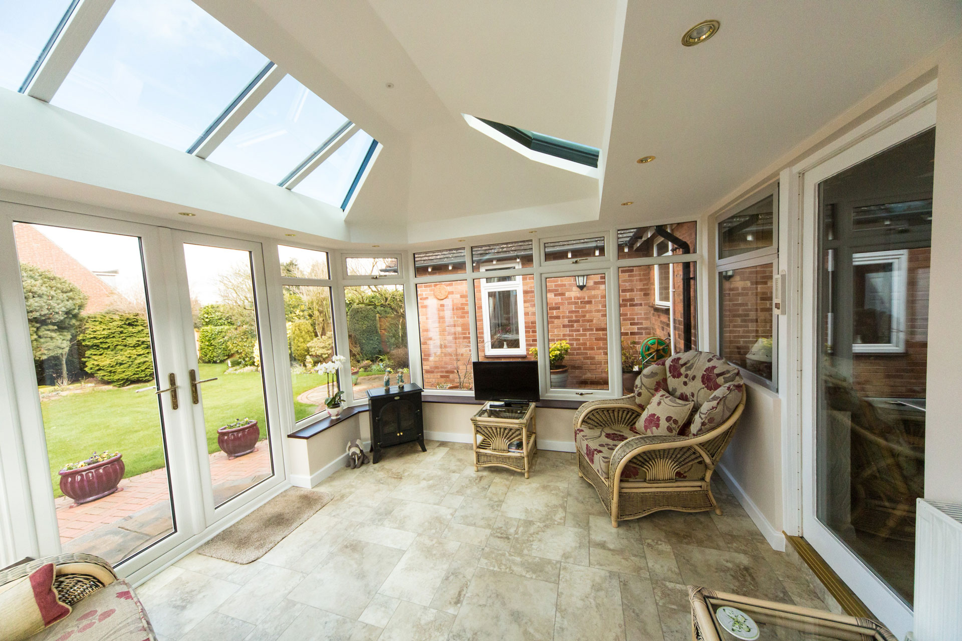white conservatory extension with roof lanterns and uPVC French doors