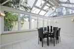 inside a white uPVC conservatory with a black table and chairs