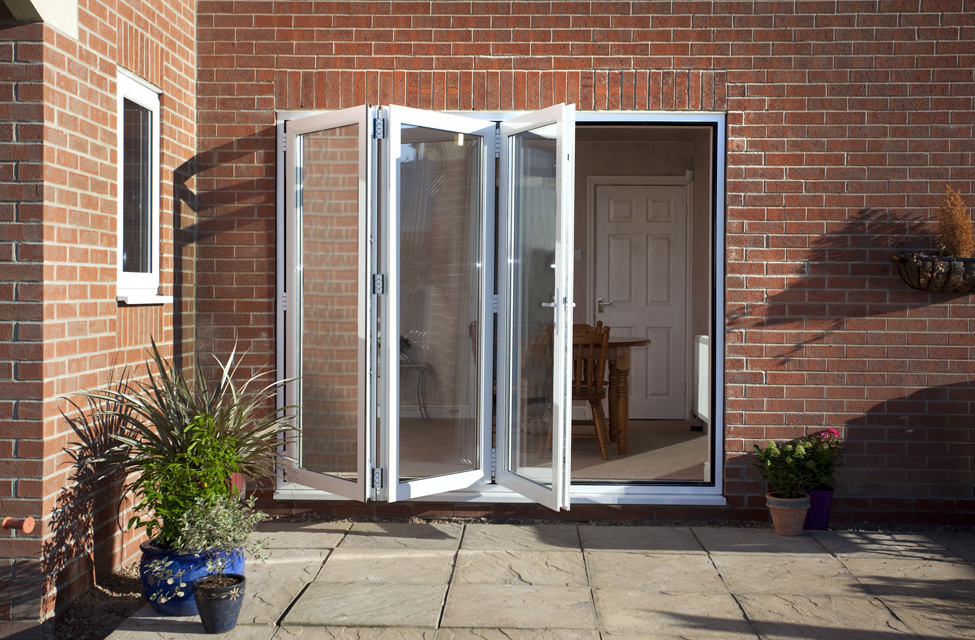 partially open white uPVC bifold doors leading to a tiled patio