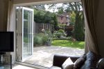 Wide open upvc white bifold doors leading to a patio and grass garden