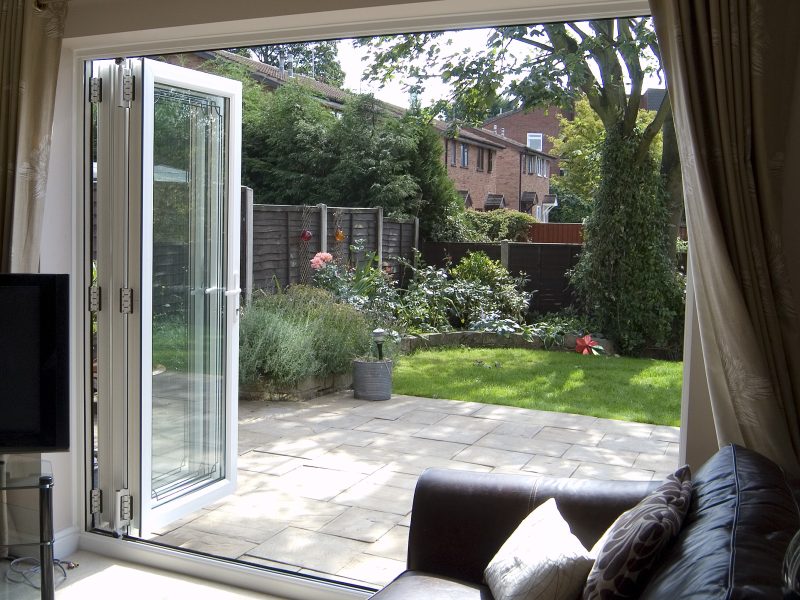 Wide open upvc white bifold doors leading to a patio and grass garden