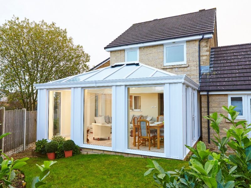 External view of a white conservatory extension with large glass panes and pointed roof