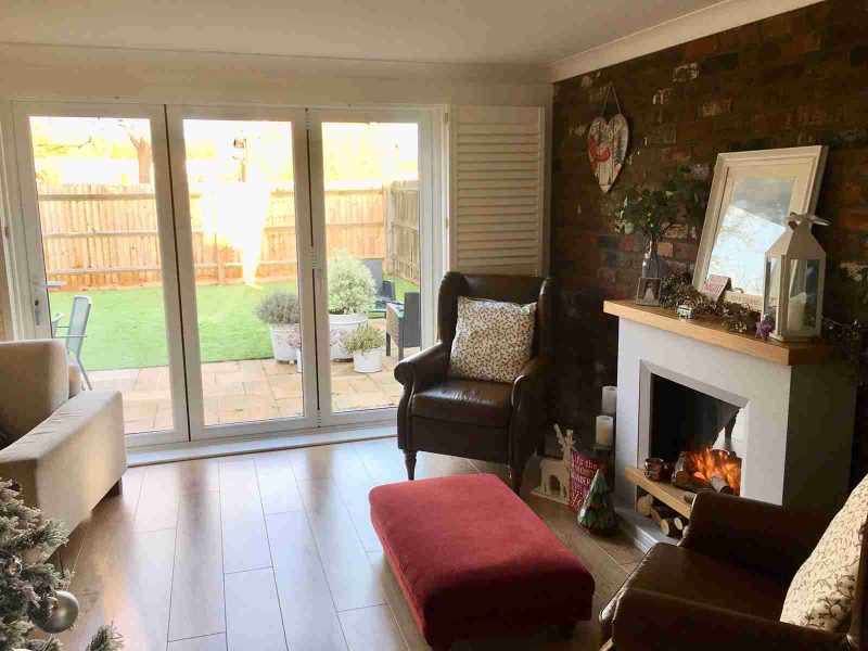 White three leaf uPVC bifold doors in a hardwood floor living room