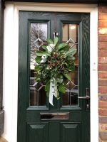 Close up of a dark green composite door with a Christmas door wreath