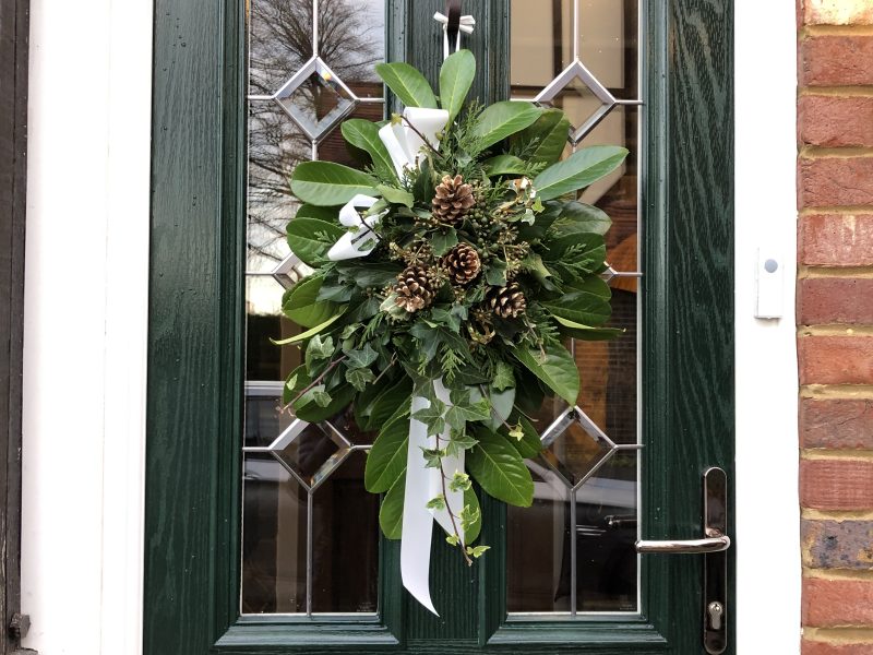 Close up of a dark green composite door with a Christmas door wreath